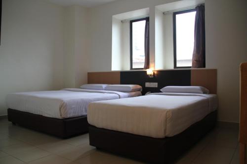 2 Betten in einem Zimmer mit 2 Fenstern in der Unterkunft Hotel New Winner in Kuala Lumpur