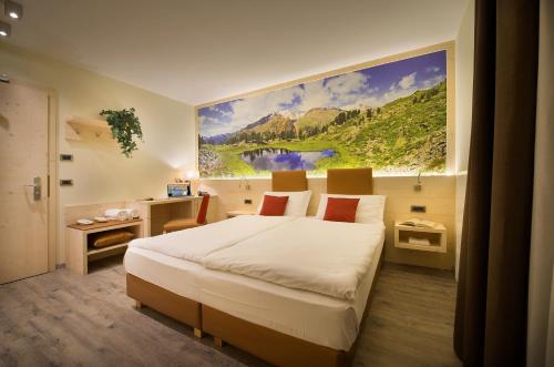 a bedroom with a large painting on the wall at Sporthotel Rosatti in Dimaro