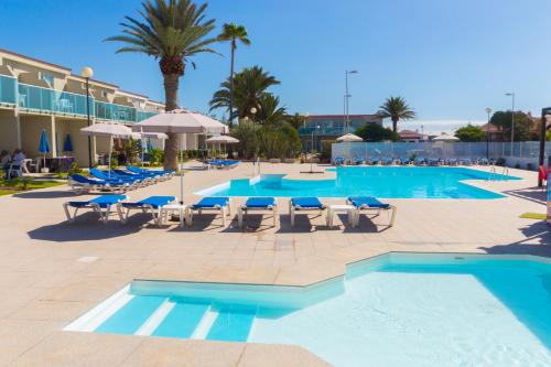 a large swimming pool with lounge chairs and umbrellas at Smartr Maspalomas Corinto in Playa del Ingles