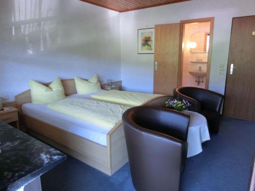 オーバーハルマースバッハにあるKempfenhofのベッド1台と椅子2脚が備わるホテルルームです。