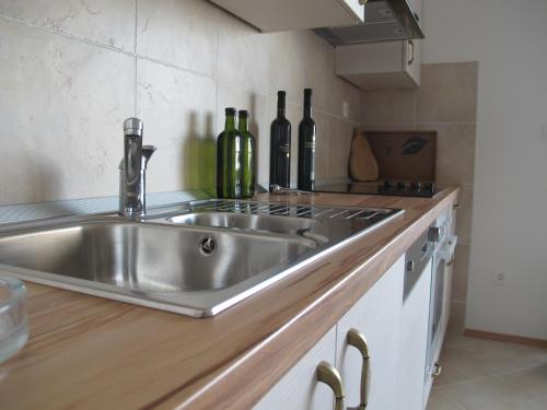 - un évier en acier inoxydable dans une cuisine avec bouteilles de vin dans l'établissement Apartment Sunset Rogoznica, à Rogoznica