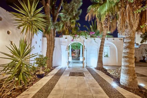 a hallway with palm trees in front of a building at Meltemi Village Hotel in Perissa