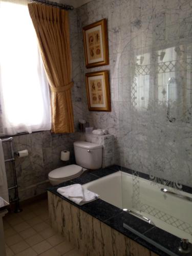 a bathroom with a tub and a toilet and a sink at The Colonnade in London