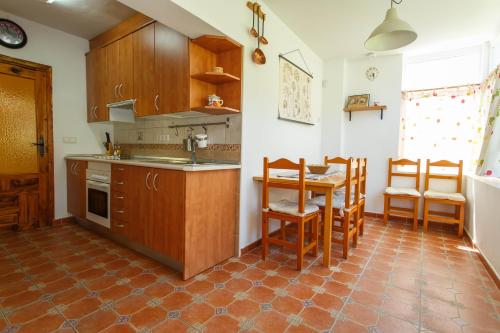 a kitchen with wooden cabinets and a table and chairs at El Bulín de la Cabrera - Pico de la Miel in La Cabrera