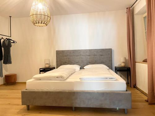 ein Schlafzimmer mit einem großen Bett mit einem grauen Kopfteil in der Unterkunft Rosa's Boutique Apartment & parking in Meran