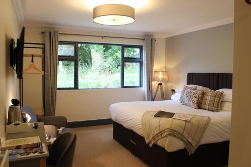 een slaapkamer met een groot bed en een raam bij Woodlands Country House & Cottage in Ireby
