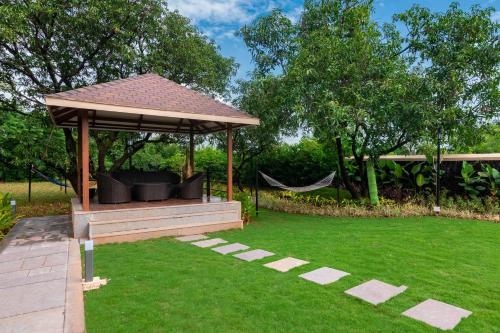 a gazebo with a hammock in a garden at Classique Woods by StayVista with Lawn with Gazebo & Bar, Indoor Fun in Karjat