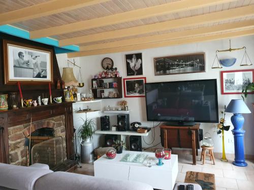 a living room with a tv and a fireplace at Le Vieux Logis in Neufchâtel-Hardelot