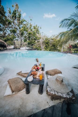 a table with food and drinks next to a swimming pool at La Cabane in Jimbaran