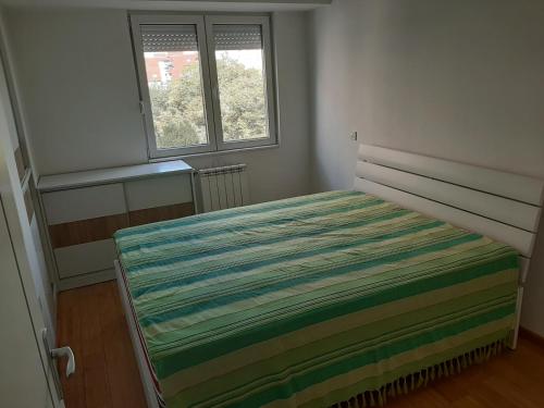 - une petite chambre avec un lit et une couverture rayée dans l'établissement Ivan2020 apartment, à Skopje