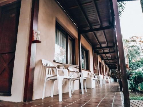 una fila de sillas blancas sentadas en un lateral de un edificio en Hotel Los Pinares en San Pedro