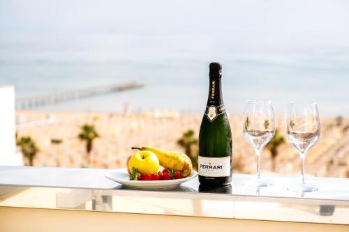 uma garrafa de vinho ao lado de um prato de frutas e copos em Hotel Saint Louis em Rimini