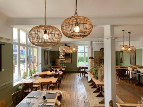 a restaurant with tables and chairs and chandeliers at HOTEL de la PLAGE in Wissant