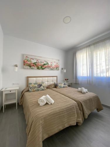 a bedroom with a large bed with towels on it at Billy's Marina 360 with pool access in Puerto de Mogán