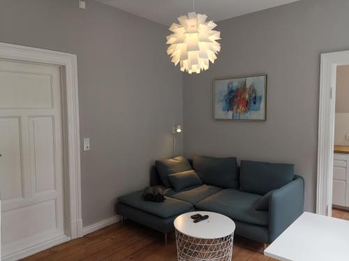 a living room with a blue couch and a chandelier at Altstadtbummel in Flensburg