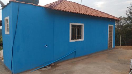 ein blaues Haus mit einem Fenster davor in der Unterkunft Casa Nascer do Sol in São Thomé das Letras