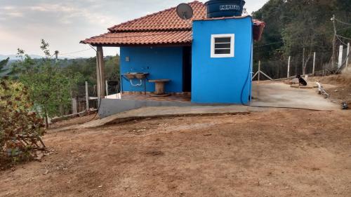 ein blaues Haus auf einem Feld mit einem unbefestigten Hof in der Unterkunft Casa Nascer do Sol in São Thomé das Letras