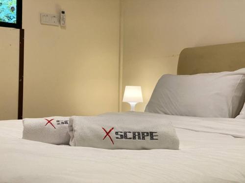 a bedroom with a bed with two pillows with the words escape at Xscape Tambun in Ipoh