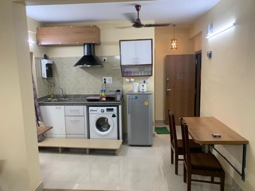 a kitchen with a washing machine and a table at Pearl by Olys Apartment in Kolkata