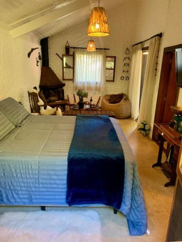 a bedroom with a bed and a living room at Chalé de luxo pertinho de Monte Verde in Monte Verde