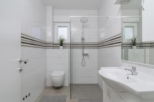 a white bathroom with a sink and a toilet at VILLA Mari with private pool in Marina