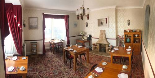 a dining room with tables and chairs and a fireplace at Doriam Guest House in Bridlington