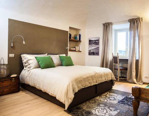 a bedroom with a large bed with green pillows at Virgula B&B in Cuneo