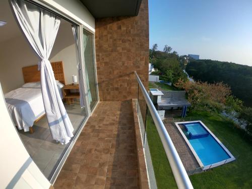 a balcony with a bed and a swimming pool at Boca PentHouses - Tampiquera in Boca del Río