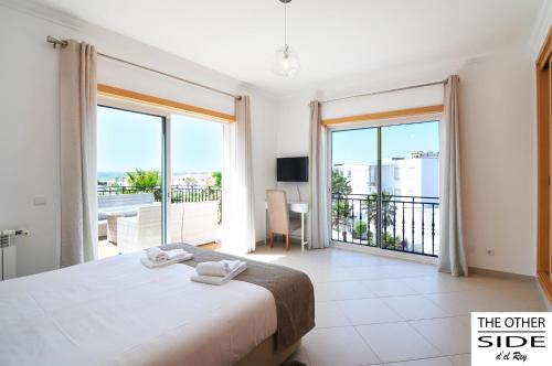 1 dormitorio con 1 cama grande y balcón en The other Side D'el Rey Apartment, en Amoreira
