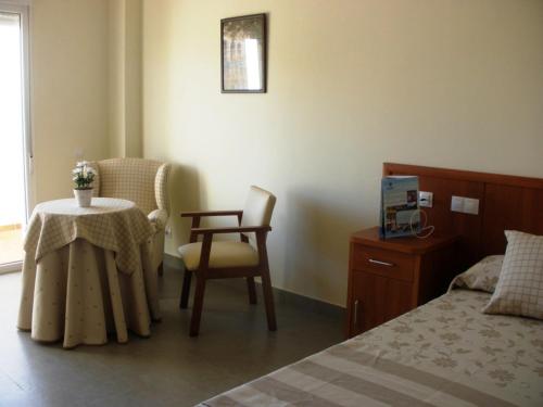 ein Schlafzimmer mit einem Bett, einem Tisch und einem Stuhl in der Unterkunft Ballesol Costablanca Senior Resort mayores de 55 años in Cala de Finestrat