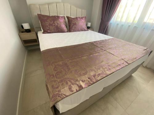 uma cama com almofadas cor-de-rosa e um edredão castanho em Vega Suites em Antalya