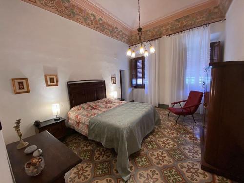 沃爾泰拉的住宿－Palazzo De Luigi，一间卧室配有一张床和一张红色椅子