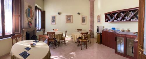 a dining room with tables and chairs and a kitchen at Dama Estense in Copparo