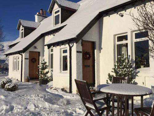 Casa blanca con mesa y sillas en la nieve en Balsporran Bed and Breakfast, en Dalwhinnie