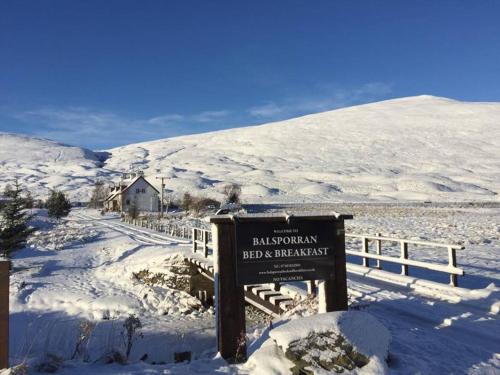una señal en la nieve junto a una valla en Balsporran Bed and Breakfast, en Dalwhinnie