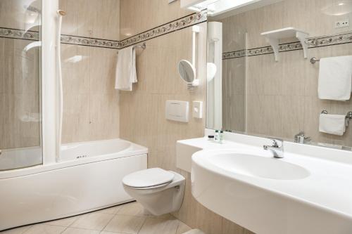 a bathroom with a toilet and a tub and a sink at NaturResidence Dolomitenhof in Siusi