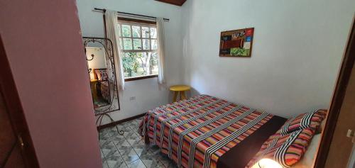 1 dormitorio con cama, espejo y ventana en Casa Charmosa, en Paraty