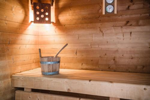 a wooden sauna with a wooden bucket and a clock at NaturResidence Dolomitenhof in Siusi