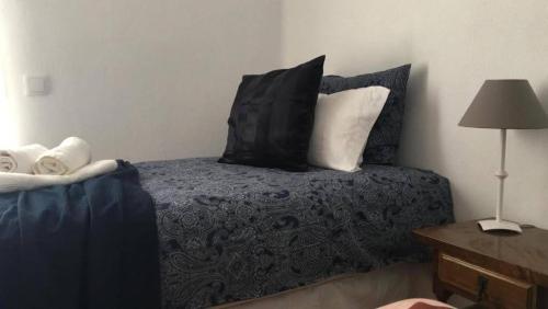 a bedroom with a bed with black pillows and a lamp at 4 persoons bungalow met gemeenschappelijk zwembad in Teulada