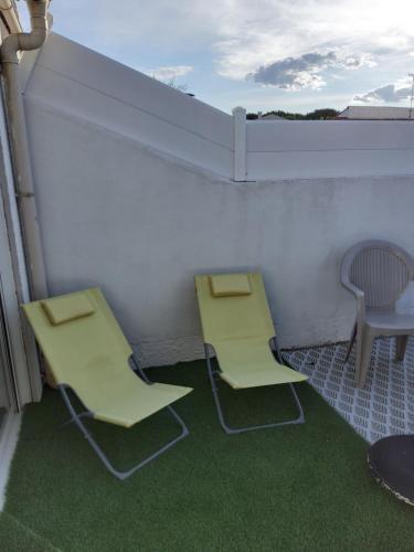 Duas cadeiras e uma mesa numa varanda com relva em Chambre d'hôtes em Lunel