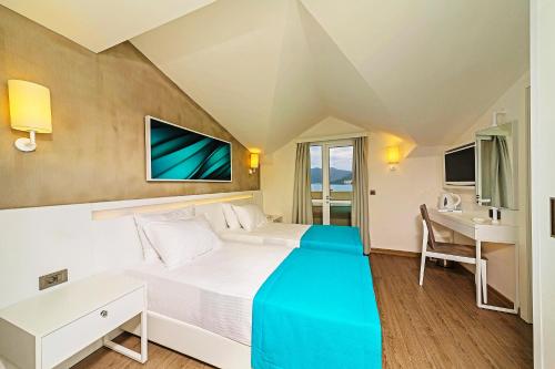a hotel room with a bed and a desk at Poseidon Hotel - Adult Only in Marmaris