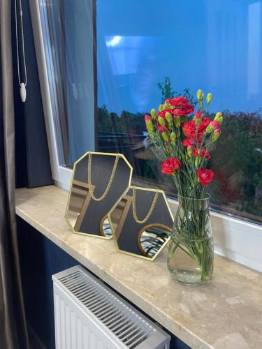 a vase of flowers on a counter with a window at Green Penthouse in Grudziądz