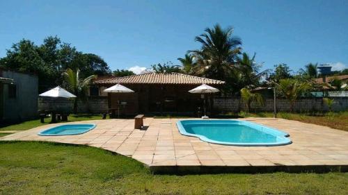een zwembad in een tuin met een patio bij Pousada Maresia do Sargi in Uruçuca