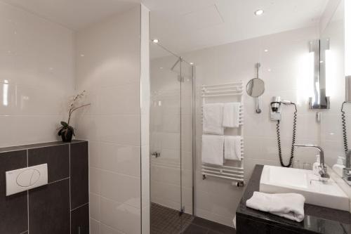 a white bathroom with a sink and a shower at Hotel am See in Salzgitter