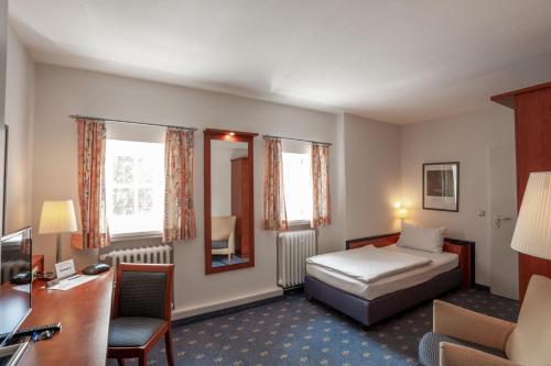 a hotel room with a bed and a desk at Hotel am See in Salzgitter
