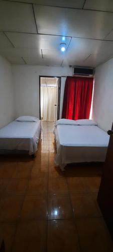 Zimmer mit 2 Betten und einem roten Vorhang in der Unterkunft Hospedaje Tropical Dreams in Corn Island