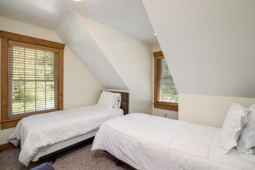 two beds in a bedroom with white walls and windows at White Pine . Trailside Lodging in Millersburg