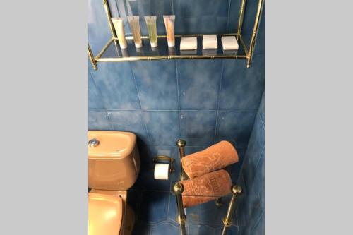 a blue tiled bathroom with a toilet and towels at Casa con jardín GRANADA, fácil aparcamiento calle in Granada