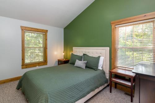 a bedroom with a bed and a desk and two windows at Blue Spruce . Trailside Lodging in Millersburg