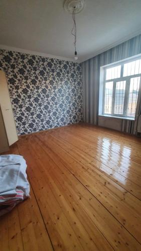 an empty room with a hard wood floor and a window at Дом в Хырдалане in Xirdalan